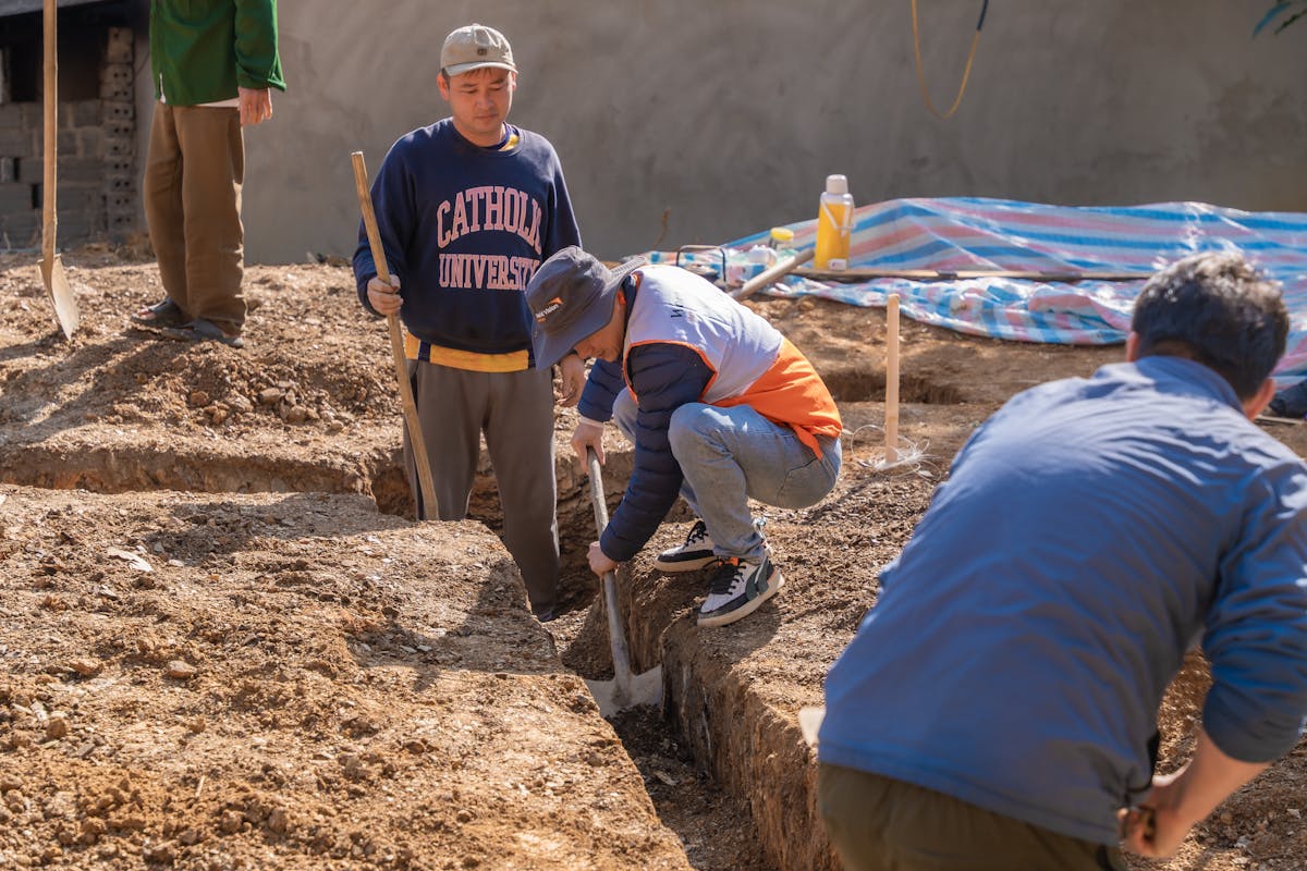 Foundation excavation — workers digging a trench on a construction site